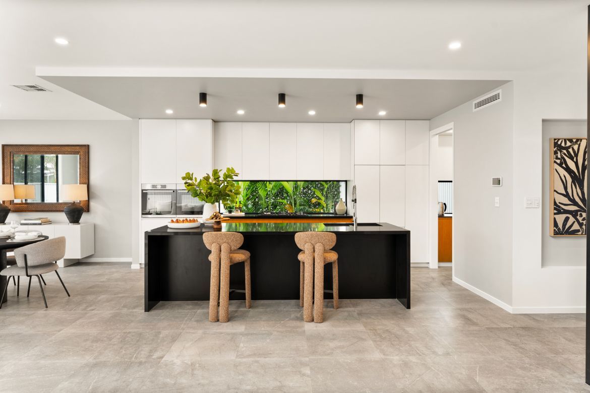 Modern entertainer’s kitchen at Prize Home 469 featuring a large black island bench, breakfast seating and white cabinetry.