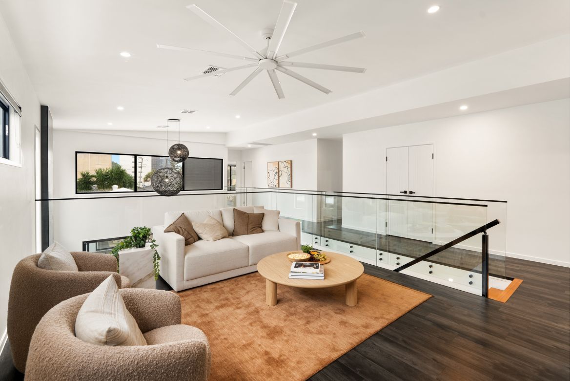 Upstairs living area at Prize Home 469 featuring a lounge setting, glass balustrade and modern open-plan design.