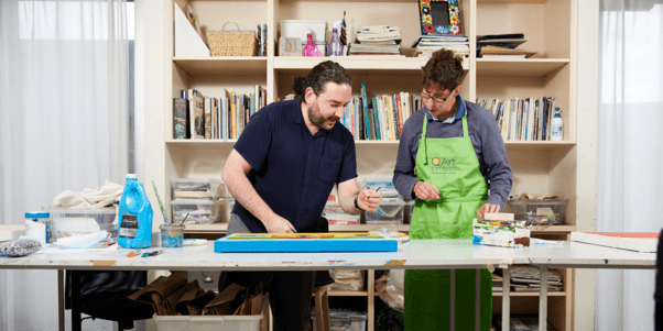 QArt Studio artist working alongside a studio supervisor (Gordon) on an original painting in the Melbourne art studio