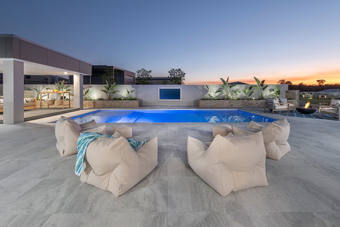 A serene poolside scene with comfortable lounge chairs and a TV for enjoying shows while lounging.