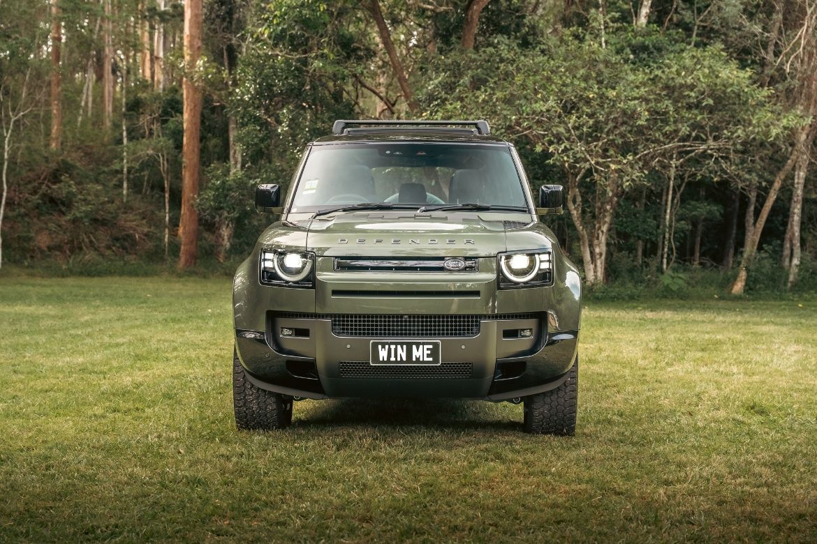 Fully kitted green V8 Land Rover Defender driving through bushland, a major prize in the Endeavour Lotteries Pay Day 220 draw