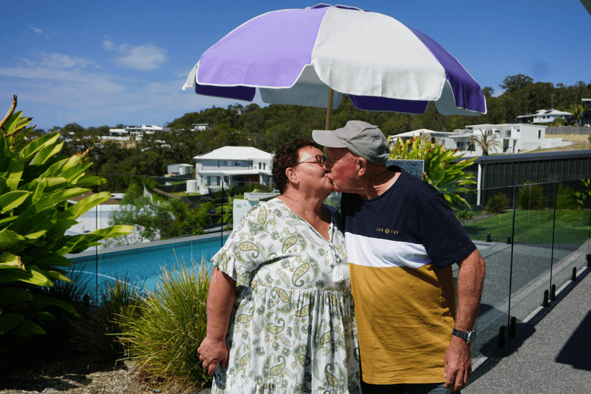 Endeavour Foundation Prize Home 450 winners, Gillian and Mark, share kiss while standing next to their brand new pool