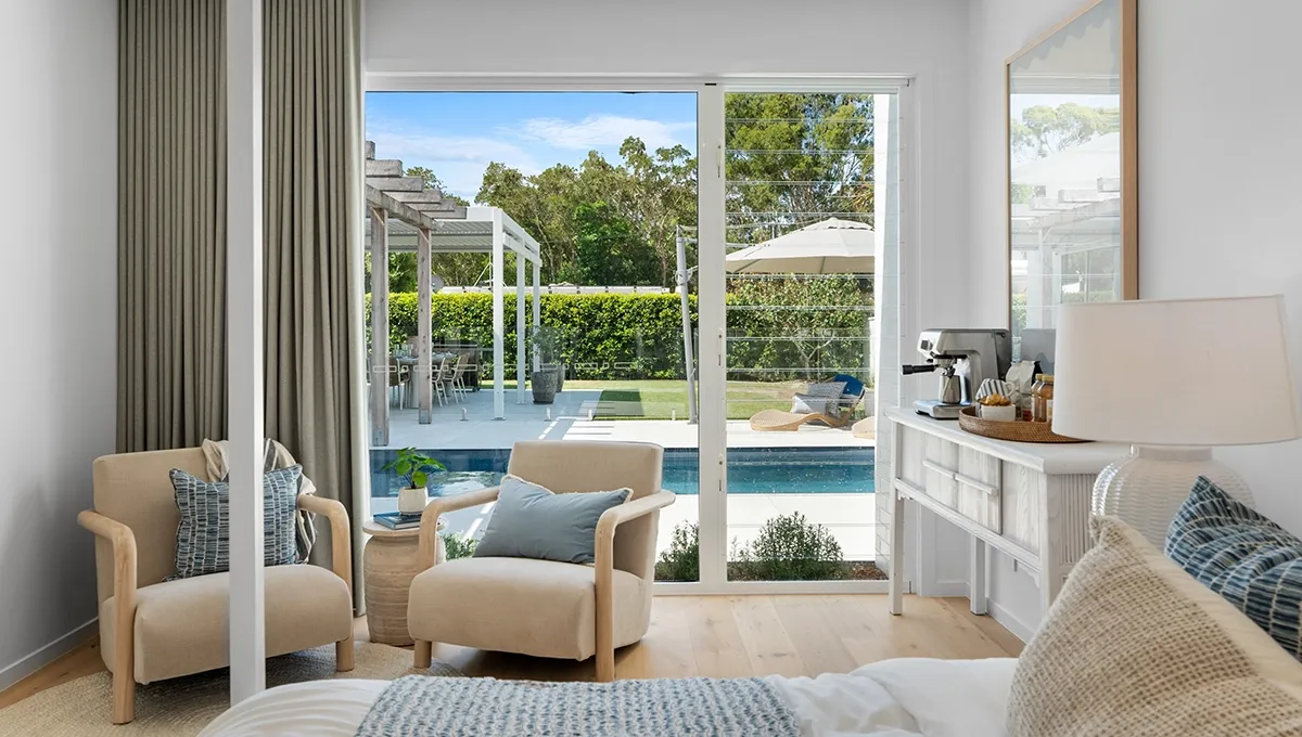 A coastal-style bedroom sitting area overlooking the pool at the Coolum Beach Prize Home.