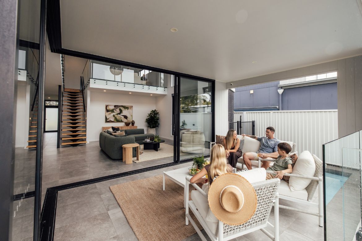 Family relaxing in the covered outdoor entertaining area overlooking the living room at Prize Home 469 in Golden Beach.