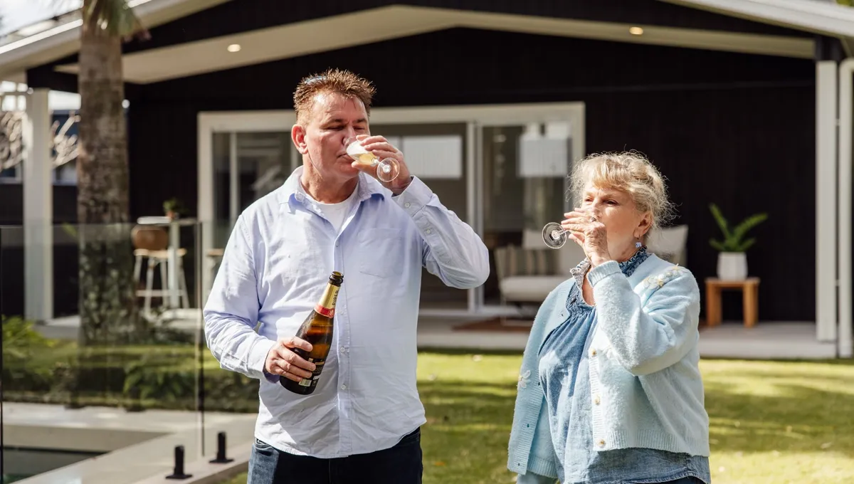 Mal laughs as he shares a glass of champagne beside his mum in the backyard of his new home.