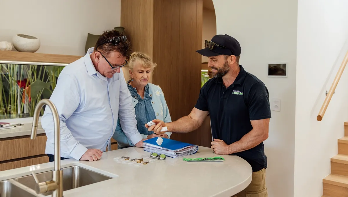 Joel hands Mal the keys and home information as Mal’s mum looks on in the kitchen.